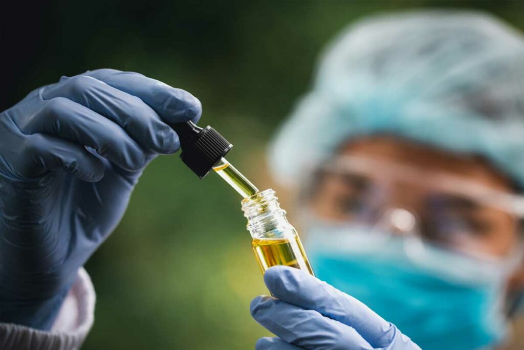 gloved hand extracting oil from a dropper